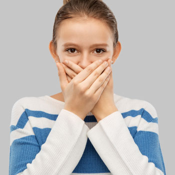 Teenage girl covering mouth by hands
